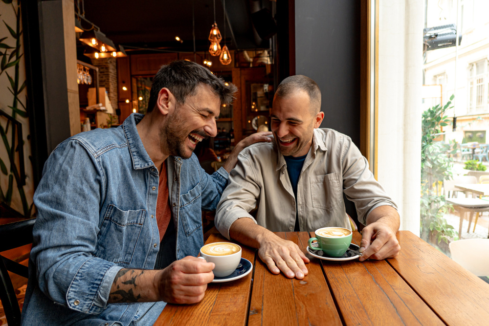 Two male friends enjoying a relaxing time together, sharing stories and laughter over coffee in a cozy café