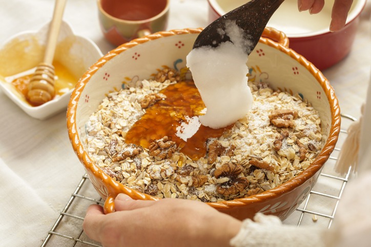 Woman making homemade granola in the kitchen. Serie of photos of all recipe's steps. Mixing all ingredients in the big bowl.