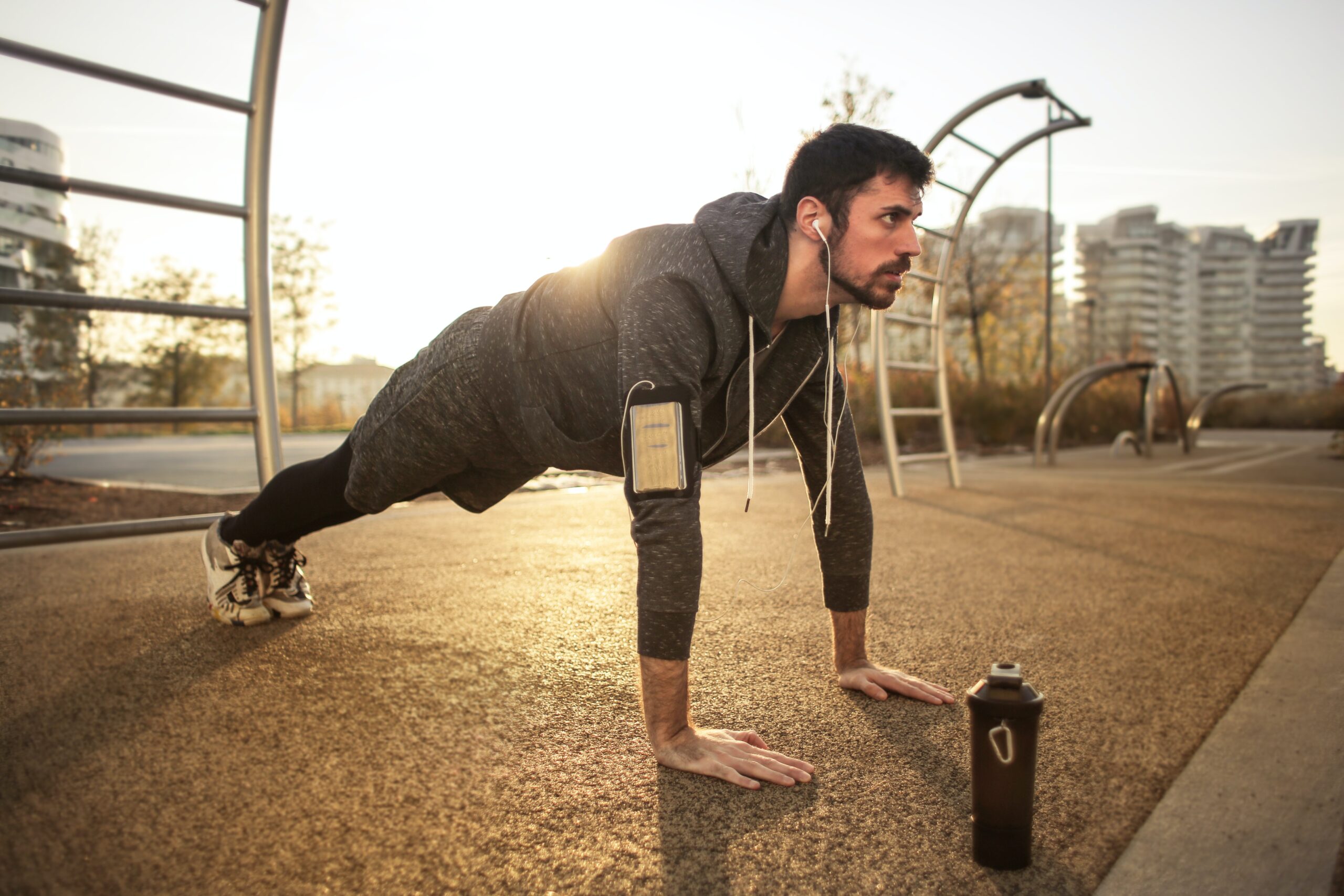 man in gray jacket doing push ups during sunrise