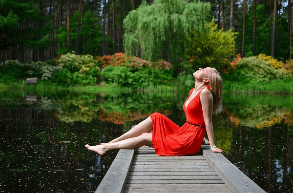 a lady dressed in red, sitting by the lake