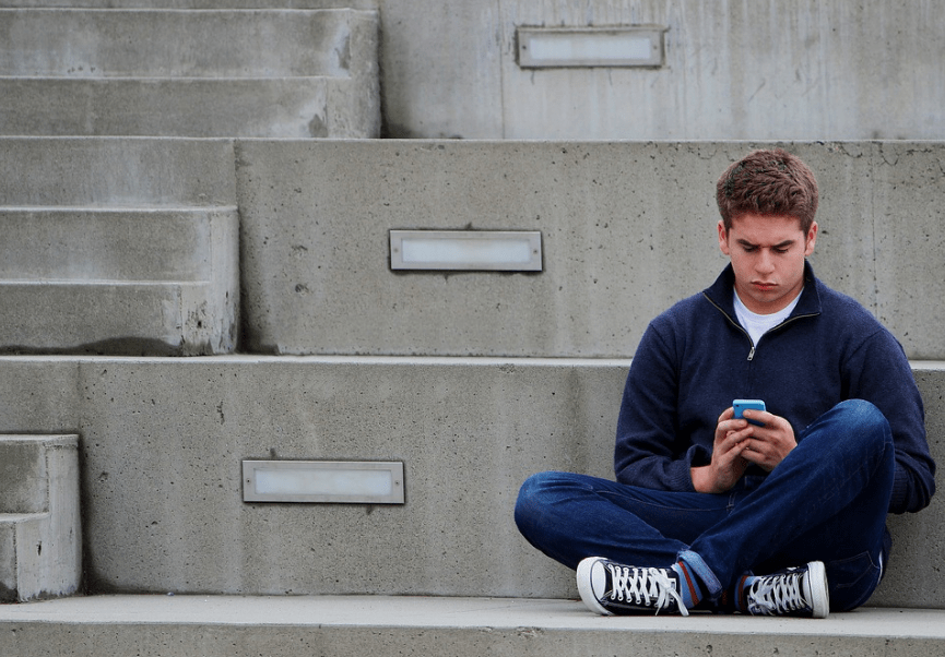 A teenager sitting alone and using his phone
