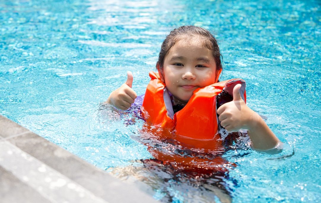 child in pool wearing life jacket