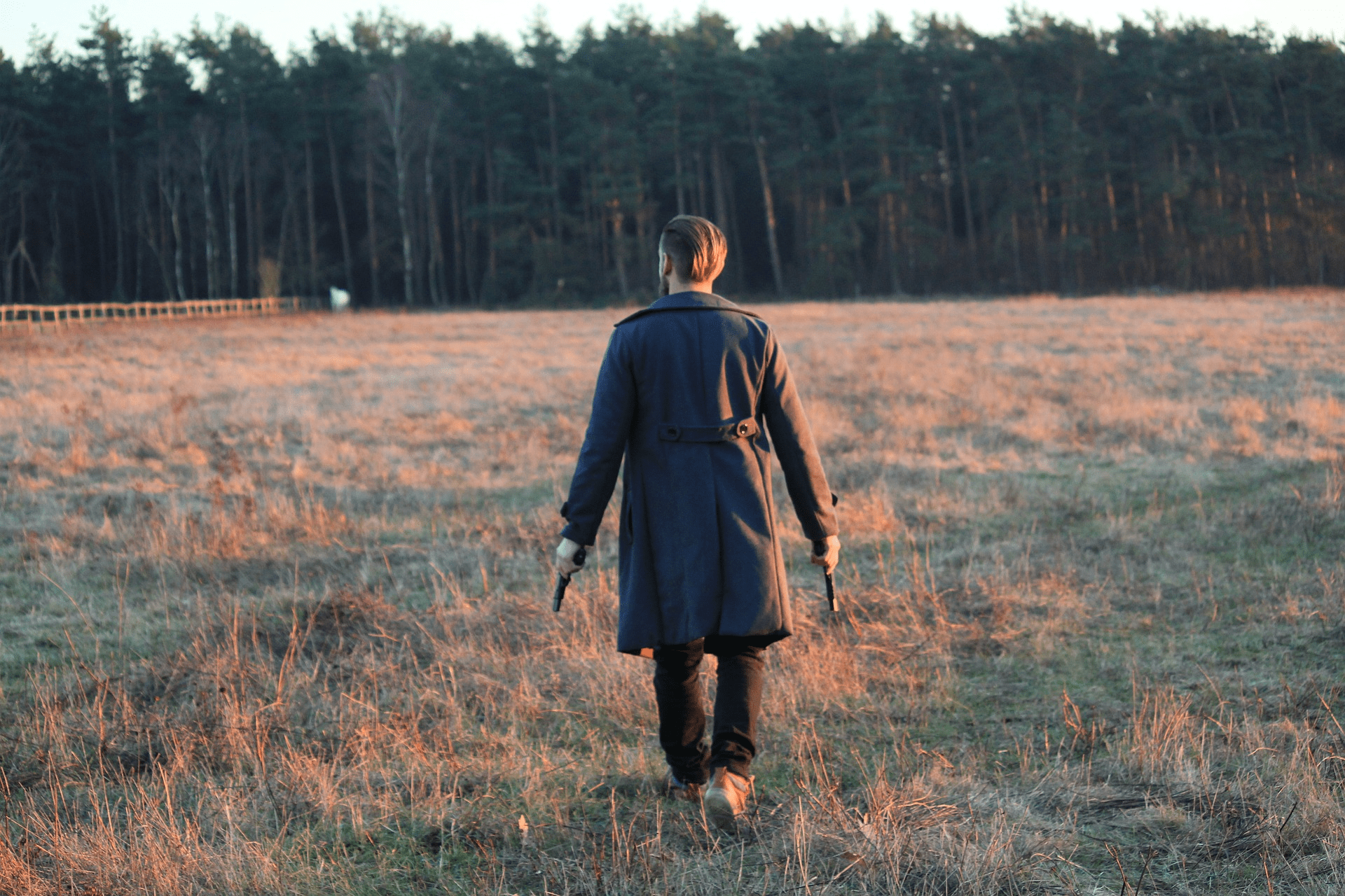 man walking in large field with black coat