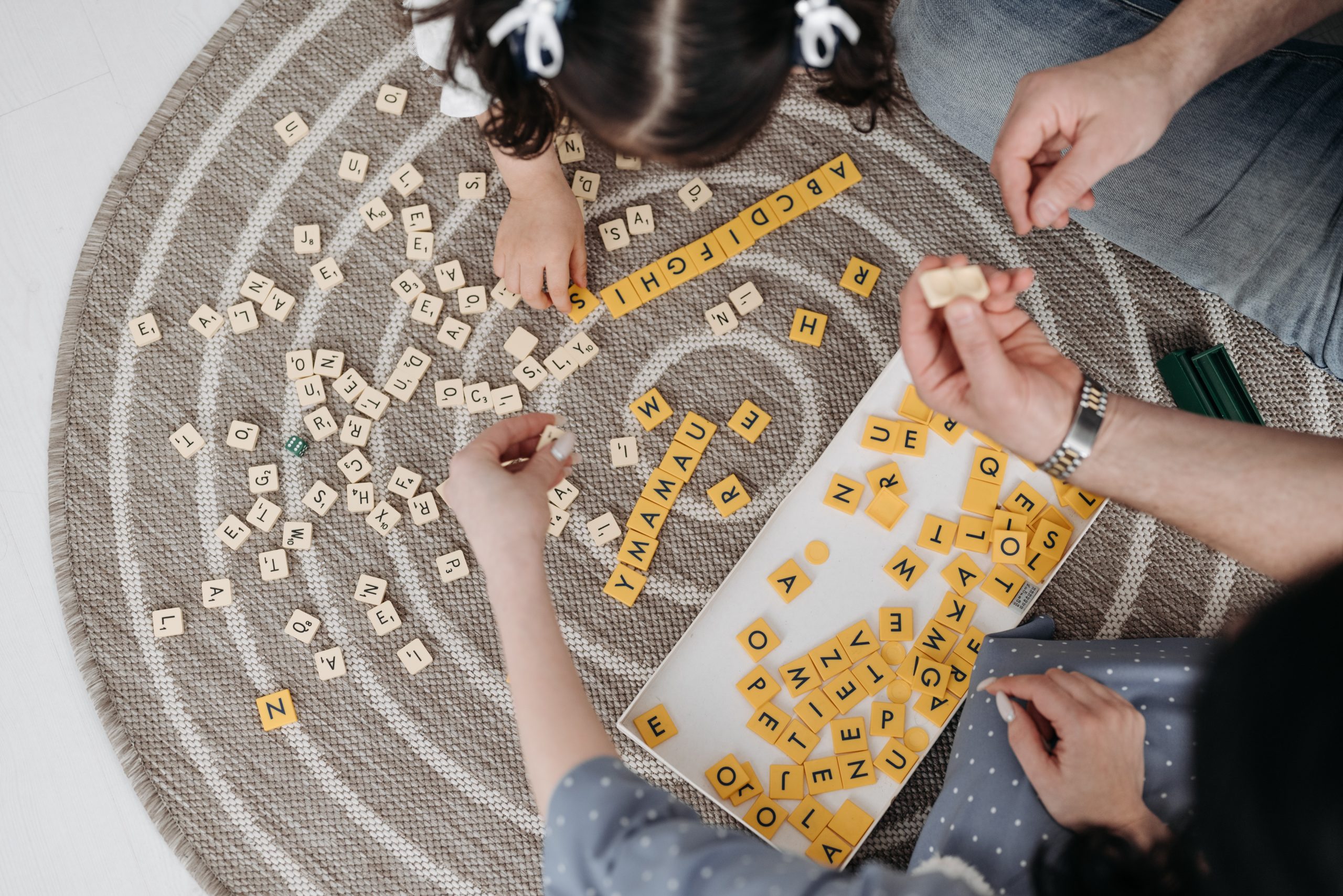 child playing scrabble with her parents