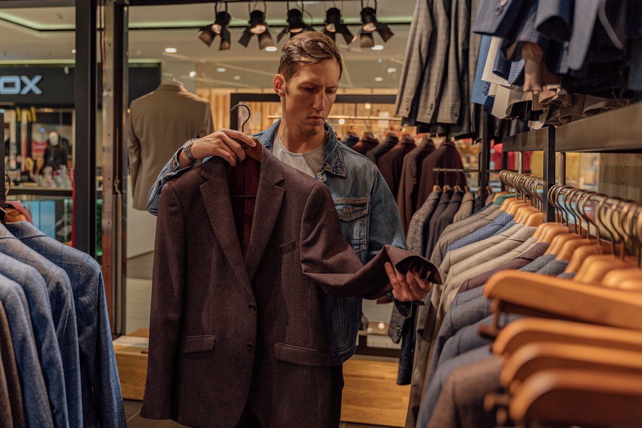 man selecting blazers in a rack
